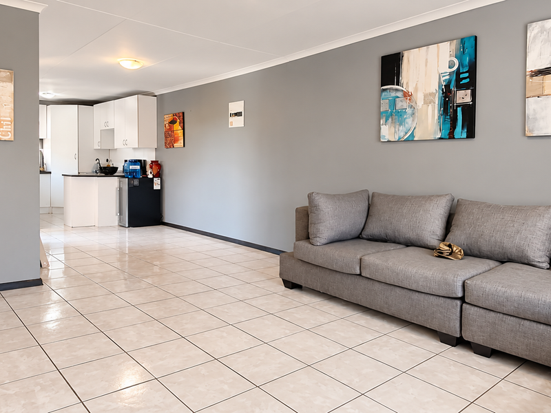 Open plan living area featuring tiled flooring and a connected kitchen space with white cabinetry.