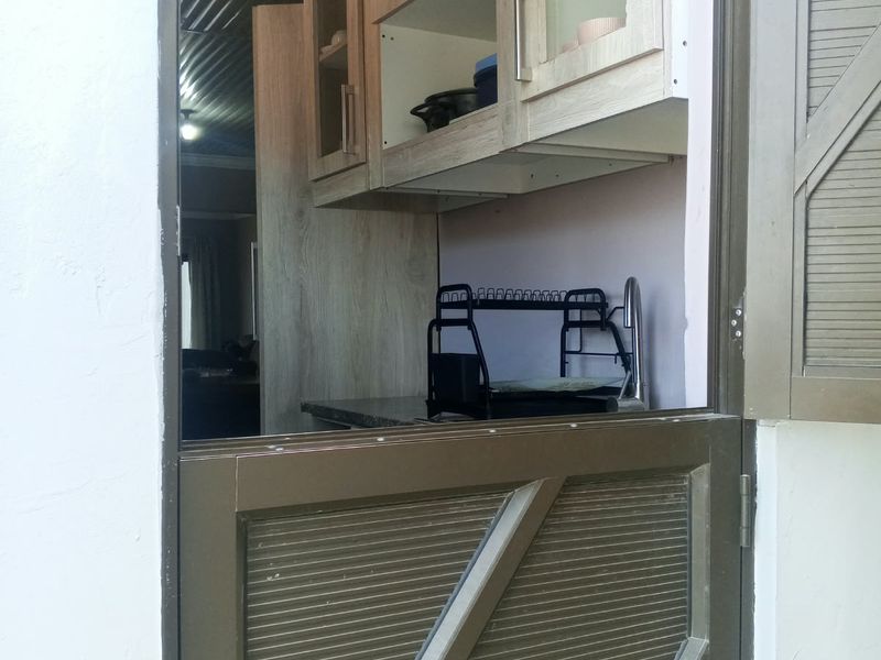 A functional scullery area featuring built-in cabinetry, a stainless steel sink, and a unique stable door entrance.