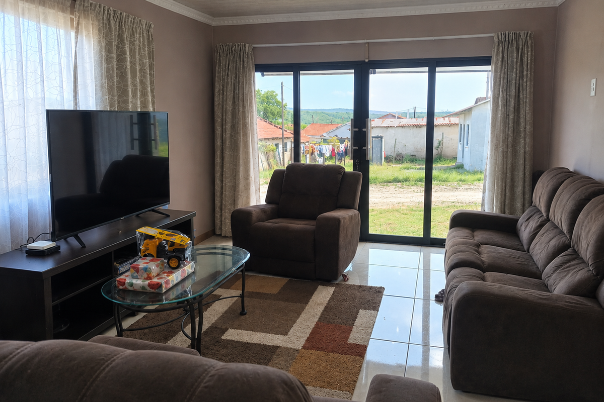 A comfortable living room featuring tiled flooring, crown molding, and large sliding glass doors that provide natural light and access to the exterior.