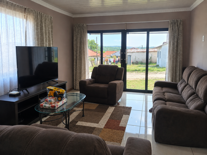 A comfortable living room featuring tiled flooring, crown molding, and large sliding glass doors that provide natural light and access to the exterior.