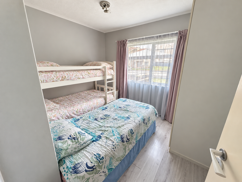 A compact bedroom featuring light-toned laminate flooring and a built-in wardrobe, offering a functional and well-maintained living space.