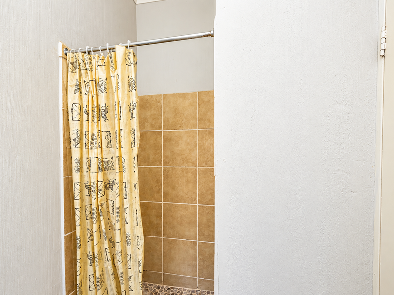 A functional shower area featuring a tiled enclosure with a pebble floor finish, ready for modern updates to enhance the bathroom aesthetic.