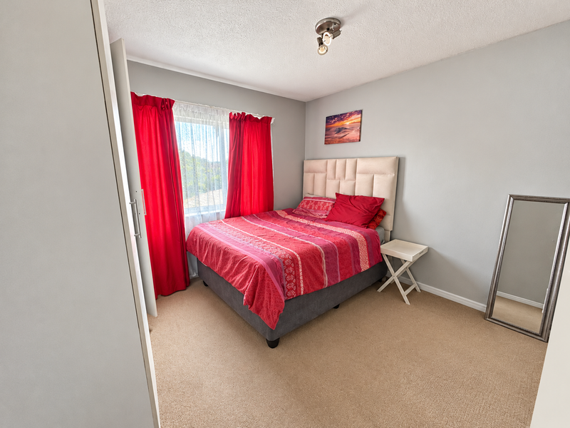 A carpeted bedroom featuring a built-in wardrobe and a ceiling light fixture, offering a functional and comfortable living space.