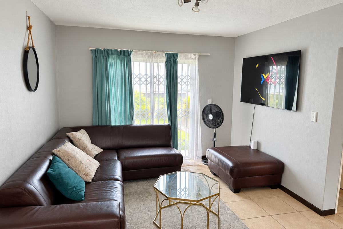 A comfortable living room featuring tiled flooring, neutral wall tones, and a security gate leading to the exterior.