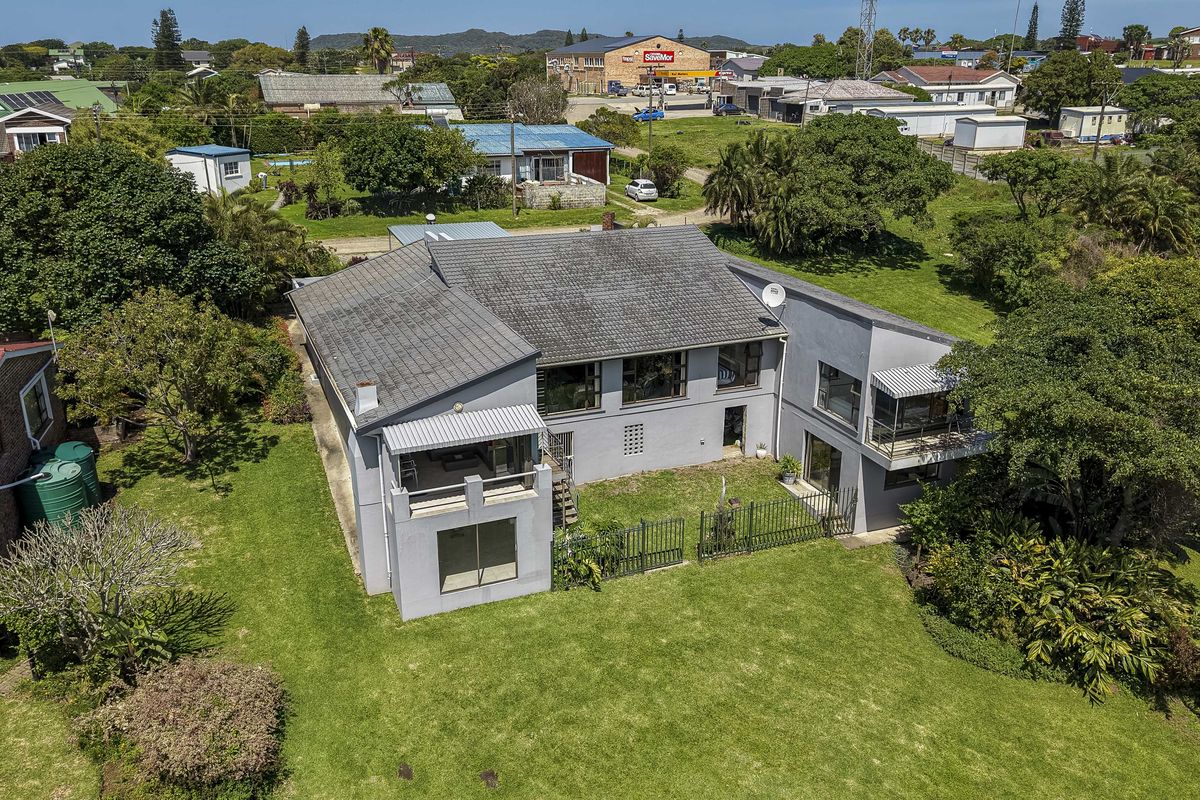 Aerial view of the property showing the rear elevation, tiled roof, balcony, and expansive garden area.