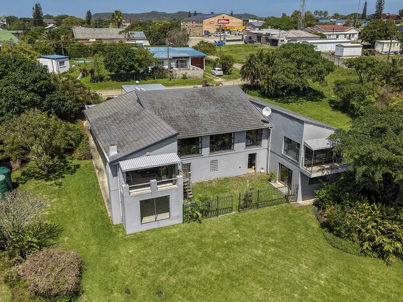 Aerial view of the property showing the rear elevation, tiled roof, balcony, and expansive garden area.