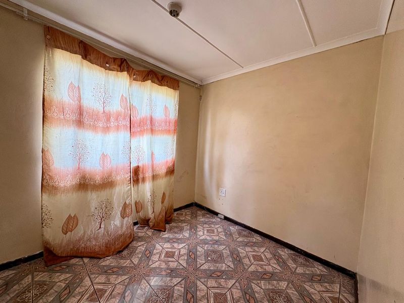 An empty bedroom featuring tiled flooring and neutral wall finishes, offering a blank canvas for potential renovation or interior design updates.