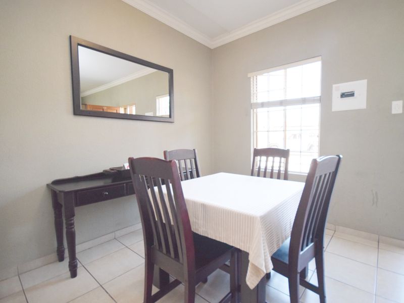 A functional dining area featuring tiled flooring, crown molding, and natural light from a window with fitted blinds.