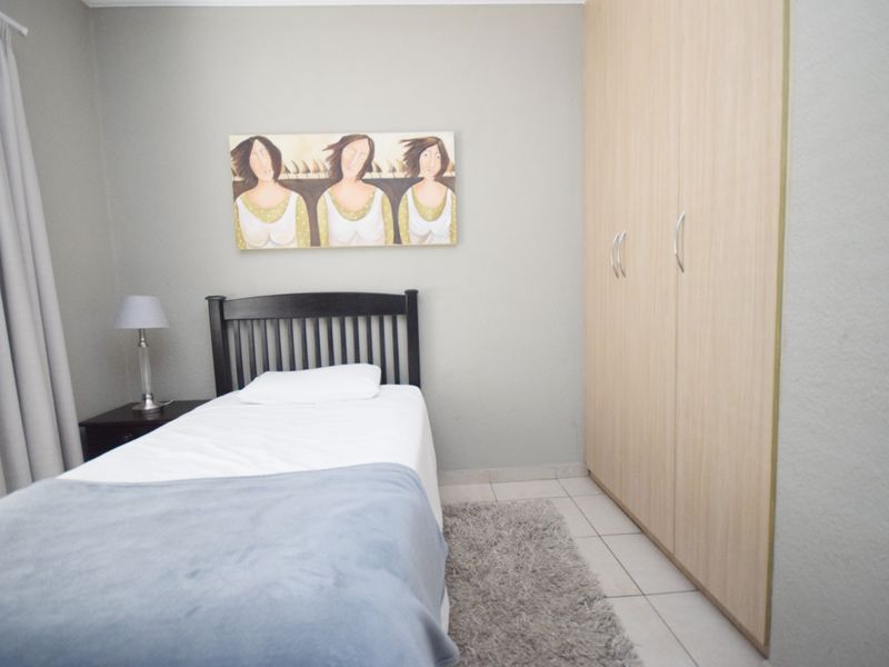 A well-maintained bedroom featuring neutral wall tones, tiled flooring, and a spacious built-in wardrobe for ample storage.