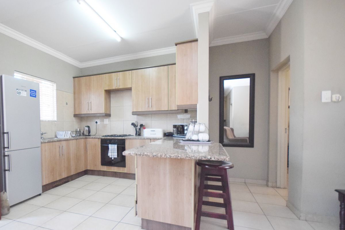Functional kitchen featuring light wood cabinetry, granite countertops, a breakfast nook, and tiled flooring, providing a practical layout for daily cooking and dining.