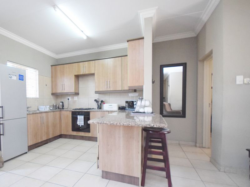 Functional kitchen featuring light wood cabinetry, granite countertops, a breakfast nook, and tiled flooring, providing a practical layout for daily cooking and dining.