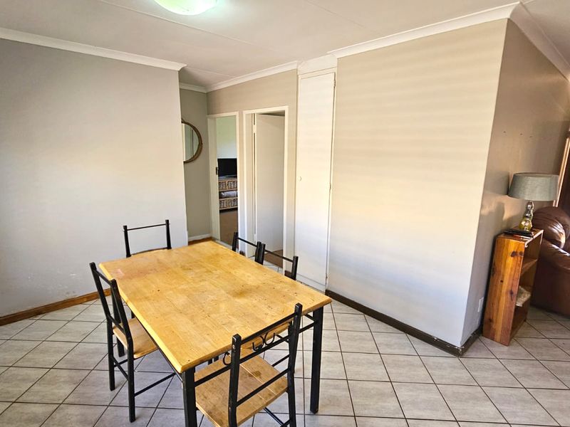Dining area featuring tiled flooring, neutral wall finishes, and a built-in storage cupboard, providing a functional space for meals.