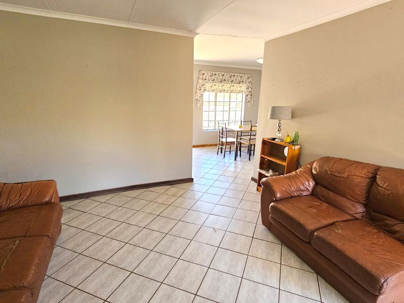 Spacious living area featuring neutral tiled flooring and coved ceilings, providing a blank canvas for potential interior updates and modern styling.