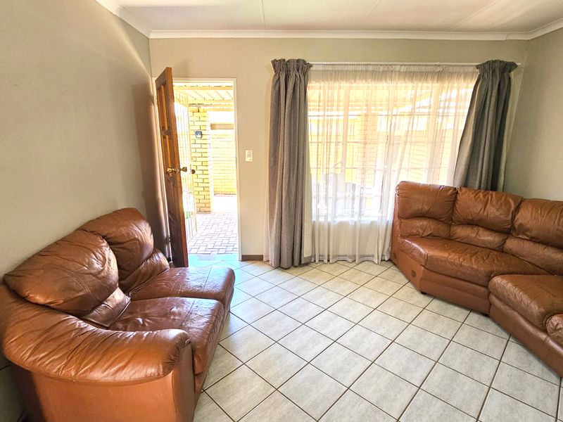 A living room featuring tiled flooring, cove cornicing, and direct access to an outdoor patio area through an external door.