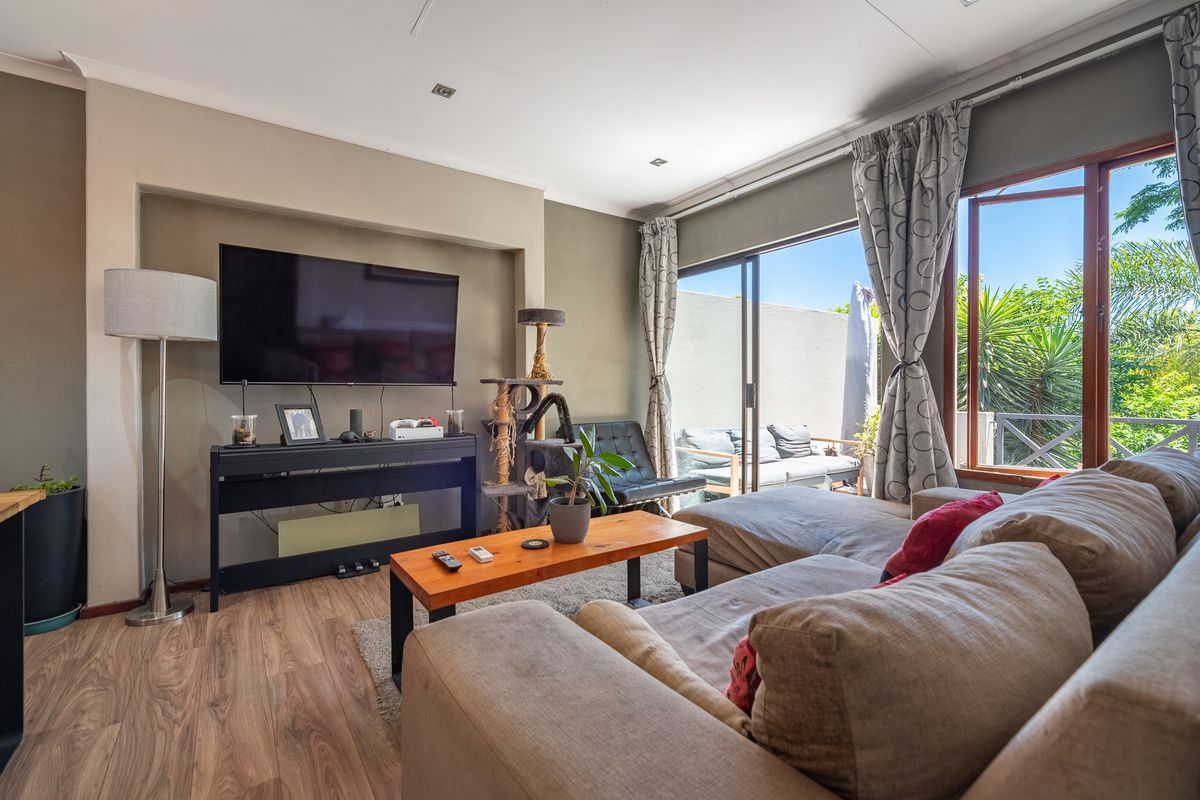 A comfortable living room featuring laminate flooring, recessed lighting, and a large sliding glass door that provides access to an outdoor patio area.