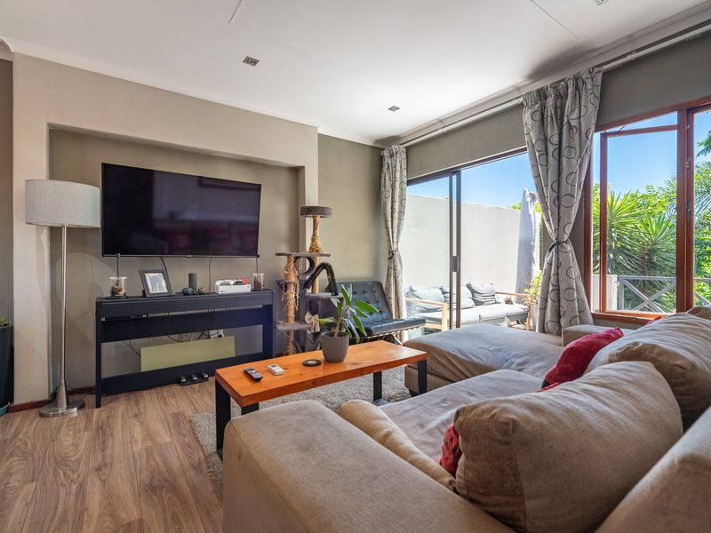 A comfortable living room featuring laminate flooring, recessed lighting, and a large sliding glass door that provides access to an outdoor patio area.