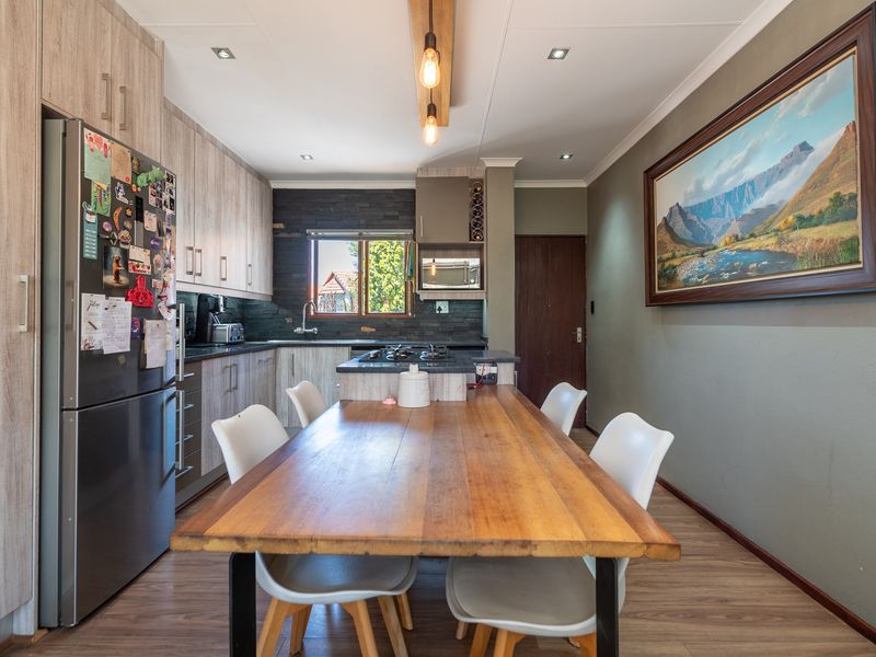 Modern open-plan kitchen featuring wood-look cabinetry, stone tile backsplash, a central island with a gas hob, and integrated lighting.