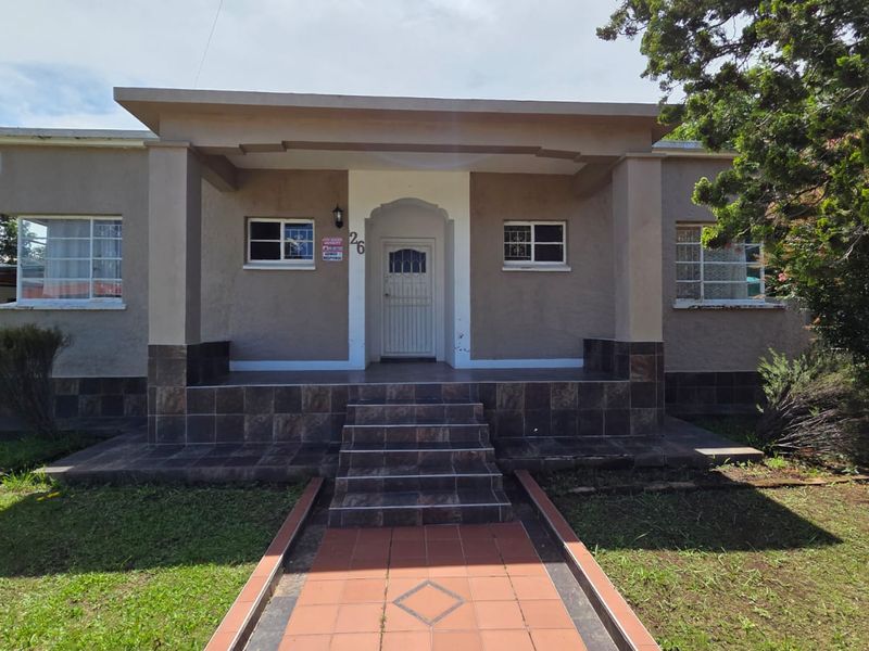 A charming single-story home featuring a tiled front porch, secure entrance, and a well-defined walkway set within a spacious front garden.