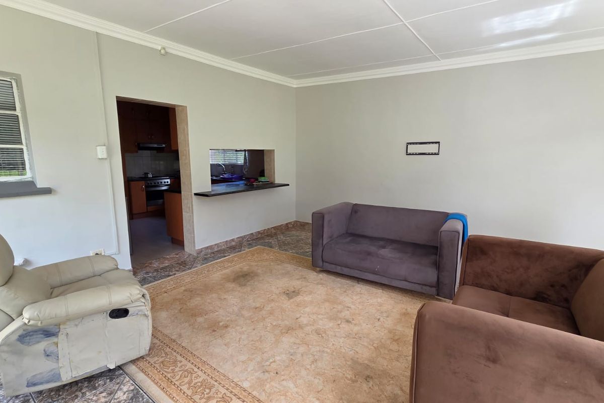 A living room featuring tiled flooring, cornicing, and a convenient serving hatch connecting to the kitchen area.