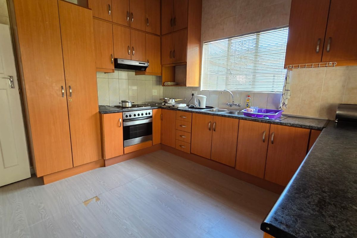 A functional kitchen featuring wood-finish cabinetry, laminate countertops, a built-in oven with extractor fan, and tiled backsplash.