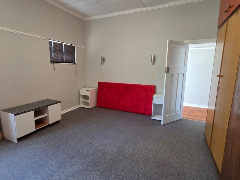 A bedroom featuring built-in cupboards, wall-mounted lighting, and carpeted flooring, offering a functional space ready for personalization.