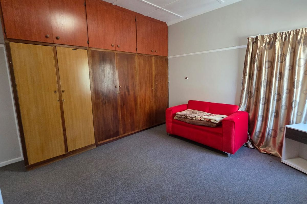 Bedroom featuring extensive built-in wooden cabinetry with overhead storage and carpeted flooring.