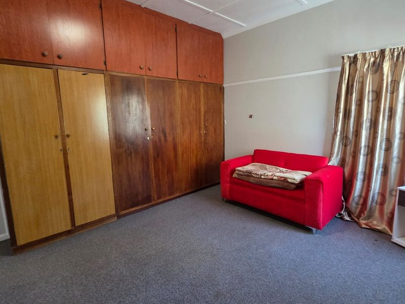 Bedroom featuring extensive built-in wooden cabinetry with overhead storage and carpeted flooring.