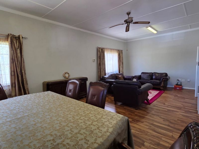 Spacious open-plan living and dining area featuring laminate flooring, a ceiling fan, and neutral wall finishes.