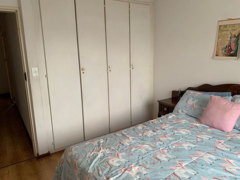 A bedroom featuring built-in cupboards and laminate flooring, offering a functional space with potential for cosmetic updates.