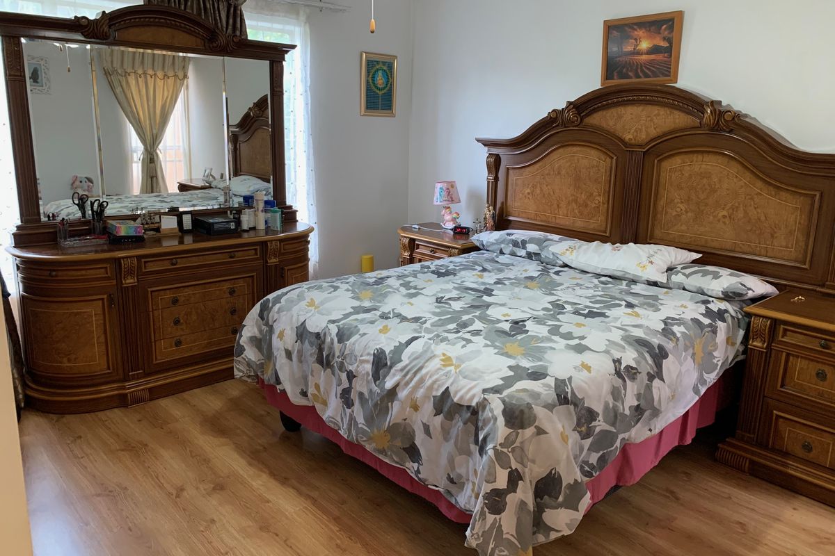 A spacious bedroom featuring laminate flooring and a ceiling fan, offering a comfortable and functional living space.