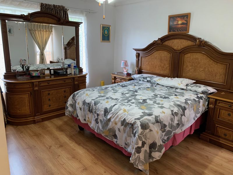 A spacious bedroom featuring laminate flooring and a ceiling fan, offering a comfortable and functional living space.