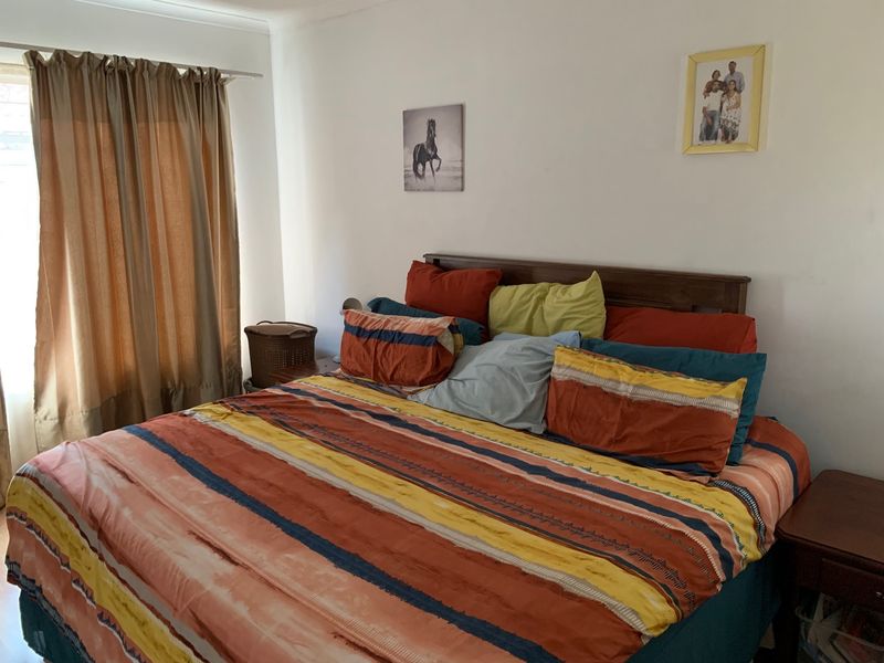 A standard bedroom featuring neutral walls and a window with installed curtain rods.