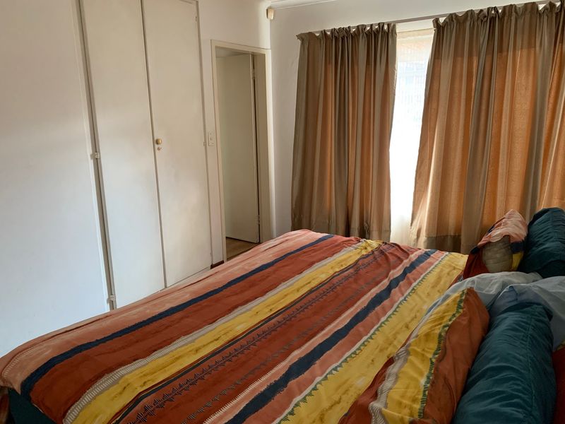 A functional bedroom featuring built-in cupboards and natural light through window coverings.