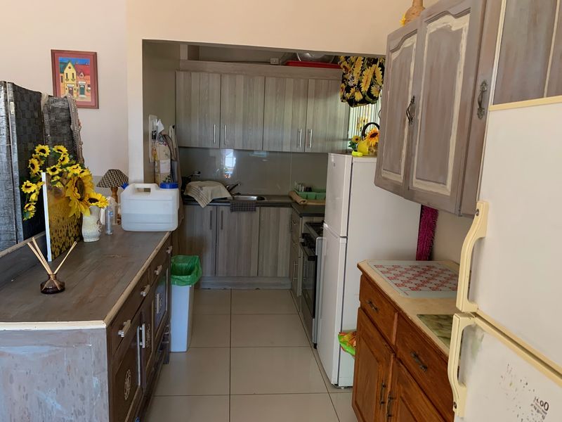 A functional kitchen area featuring built-in cabinetry, tiled flooring, and a stainless steel sink, offering a practical layout for daily meal preparation.