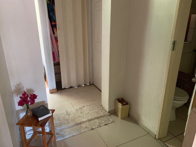A functional hallway area featuring tiled flooring and access to adjacent rooms via a folding door and standard internal door.