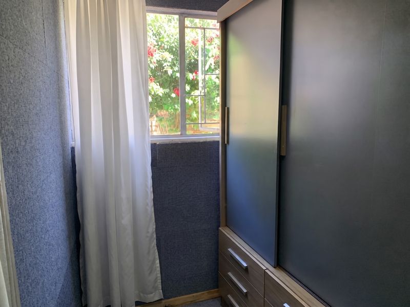A bedroom featuring a built-in sliding door wardrobe and a window with garden views.