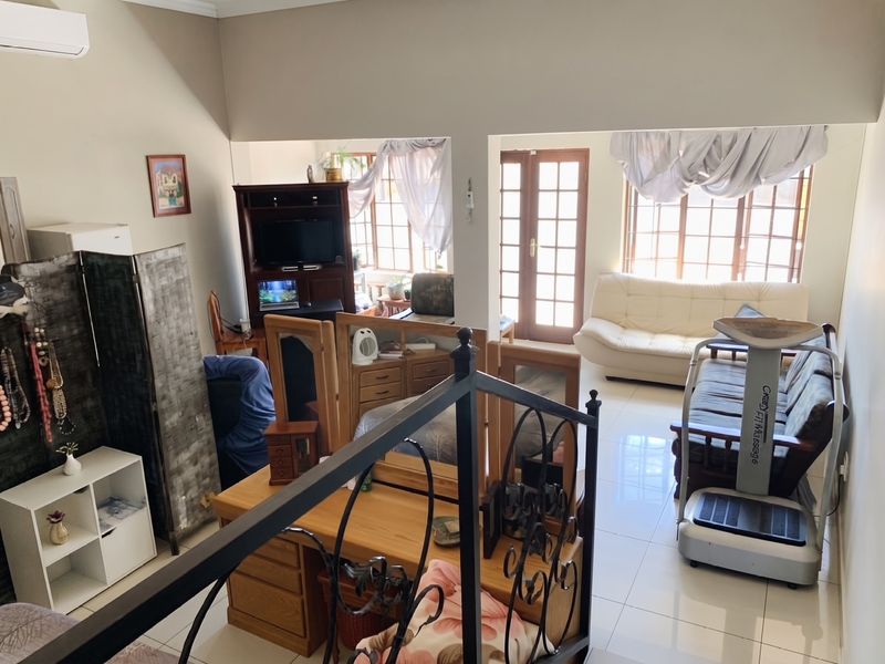Spacious open-plan living area featuring tiled flooring, wrought iron staircase detailing, and natural light through french doors and multi-pane windows.