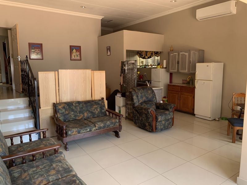 Open-plan living area featuring tiled flooring, recessed lighting, and a split-system air conditioner, seamlessly connecting to a functional kitchen space.