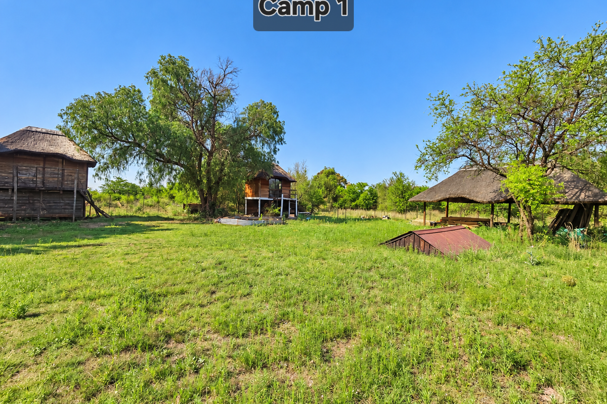 Expansive farm grounds featuring multiple thatched-roof timber structures, mature trees, and open grassy areas suitable for rural development or recreational use.