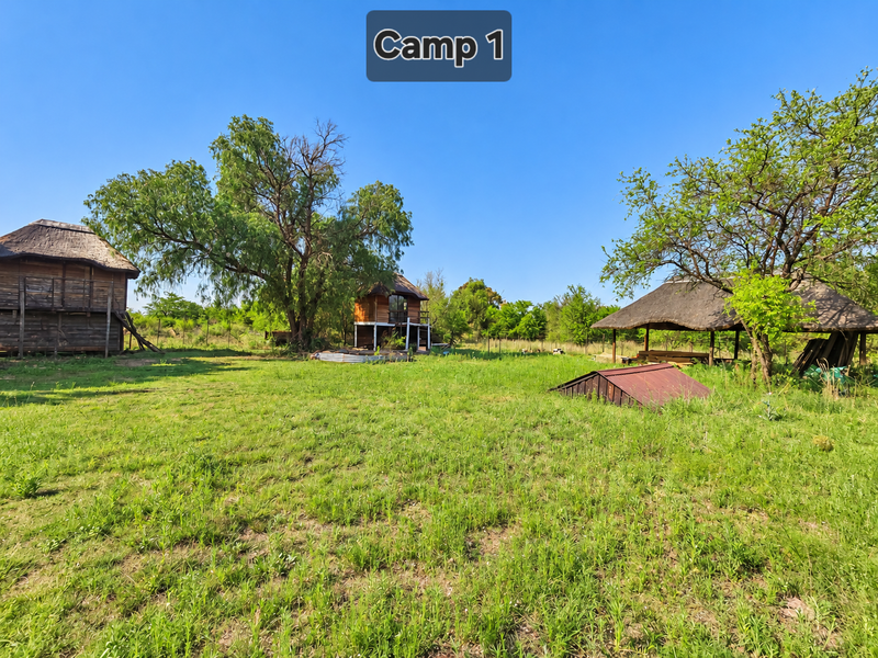 Expansive farm grounds featuring multiple thatched-roof timber structures, mature trees, and open grassy areas suitable for rural development or recreational use.