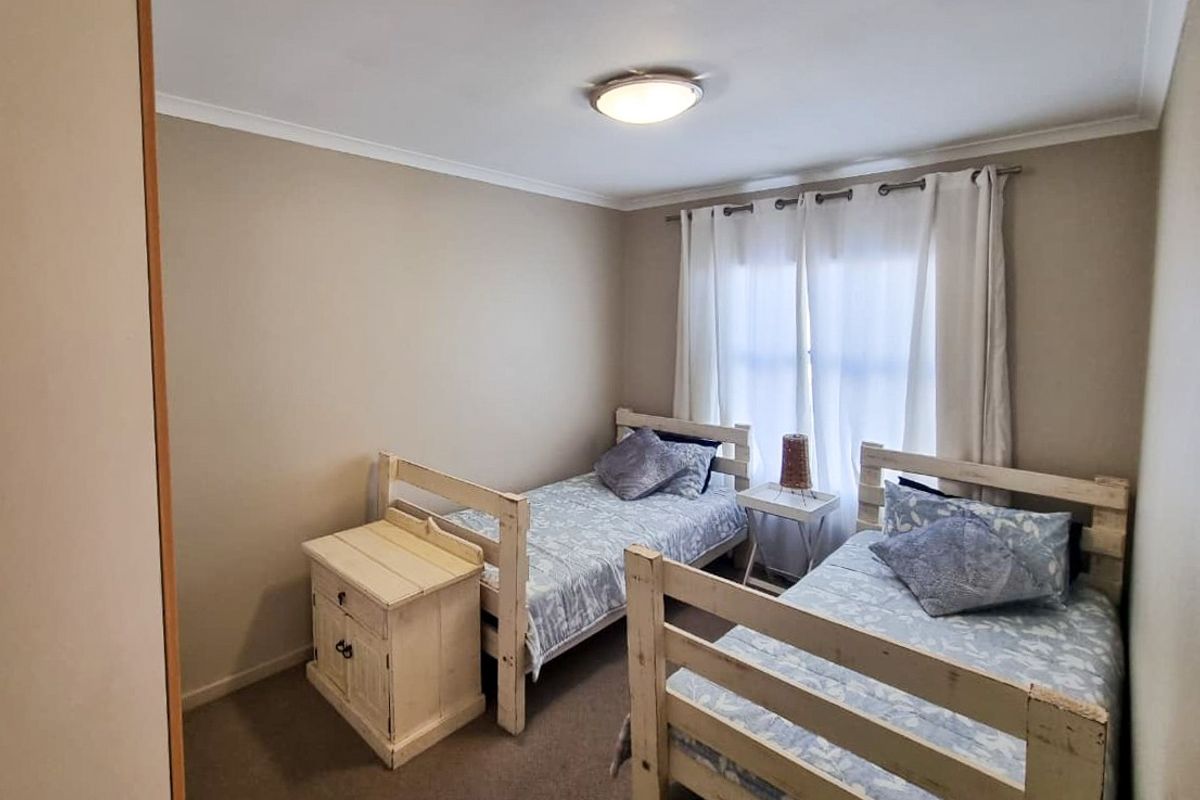 A functional bedroom featuring neutral wall tones, carpeted flooring, and a window with curtain rod installation.