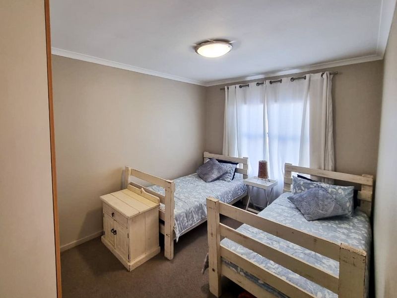 A functional bedroom featuring neutral wall tones, carpeted flooring, and a window with curtain rod installation.