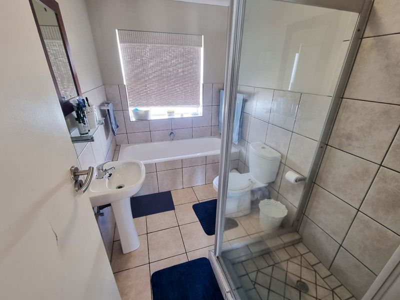 A functional bathroom featuring a pedestal basin, a built-in bathtub, and a separate shower enclosure with tiled finishes throughout.