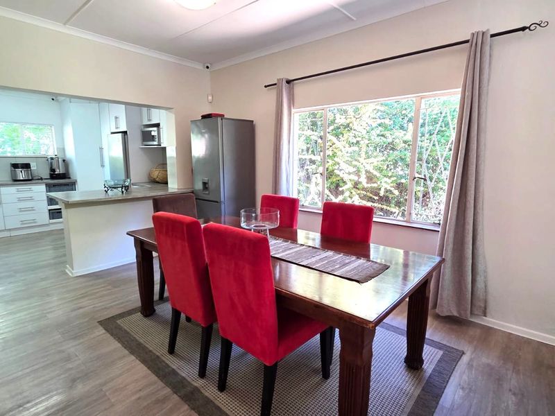 Open-plan dining area flowing into a functional kitchen with modern cabinetry, built-in appliances, and laminate flooring throughout.