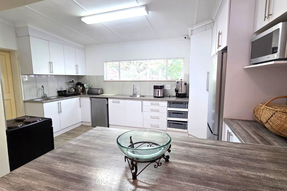 A functional kitchen featuring white cabinetry, laminate countertops, a double sink, and a built-in microwave with ample storage space.