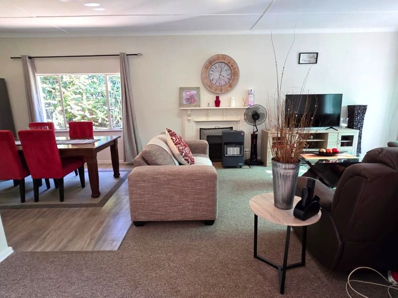 Spacious open-plan living and dining area featuring a fireplace mantel, large windows, and a combination of carpet and laminate flooring.