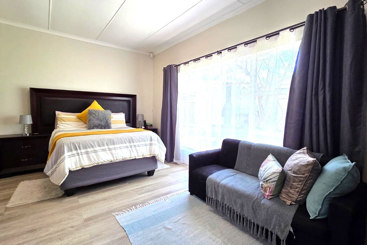 Spacious bedroom featuring light-toned laminate flooring and a large window that allows for ample natural light.