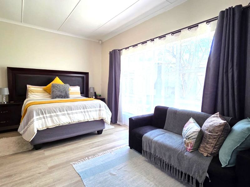Spacious bedroom featuring light-toned laminate flooring and a large window that allows for ample natural light.