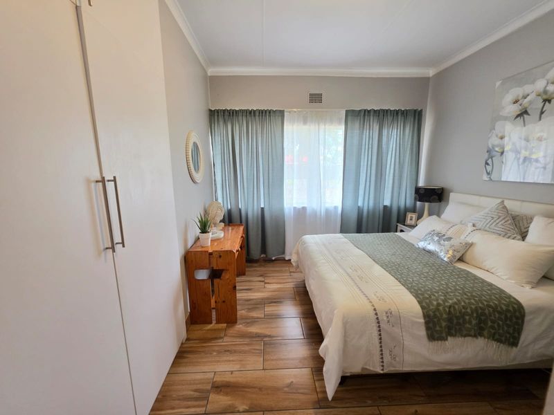 A well-maintained bedroom featuring modern wood-look tiled flooring and ample built-in cupboard storage.