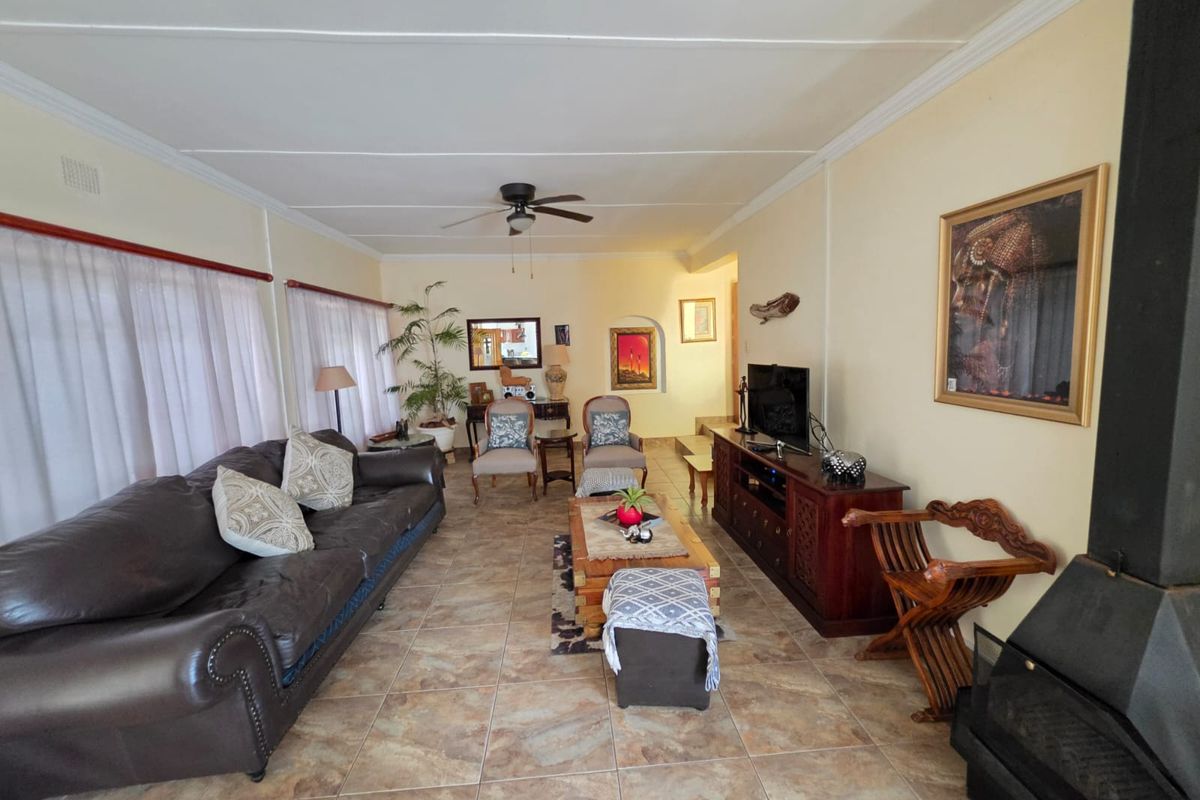 Spacious living room featuring tiled flooring, a ceiling fan, and a built-in fireplace, offering a comfortable and functional family living space.